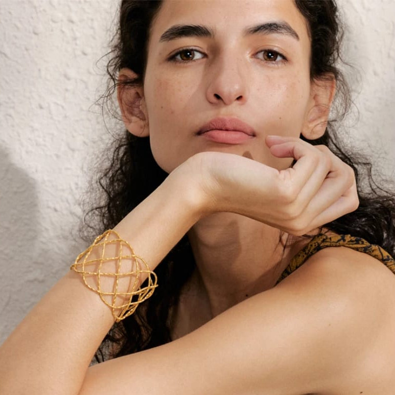 Woman wearing a gold bracelet with a textured background